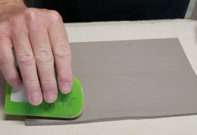 picture of clay slab with person using a rib. click more details to sign up for a handbuilding class